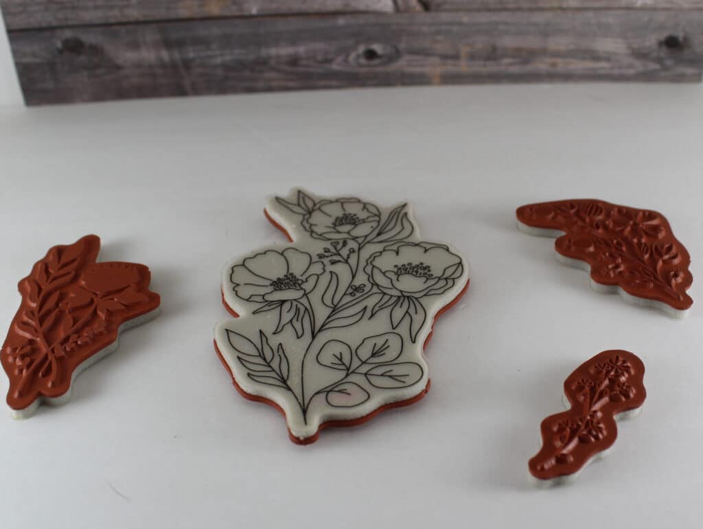 Sample of cling mount stamps center stamp is label side up with flowers one to the left and two on the right show red rubbers side.